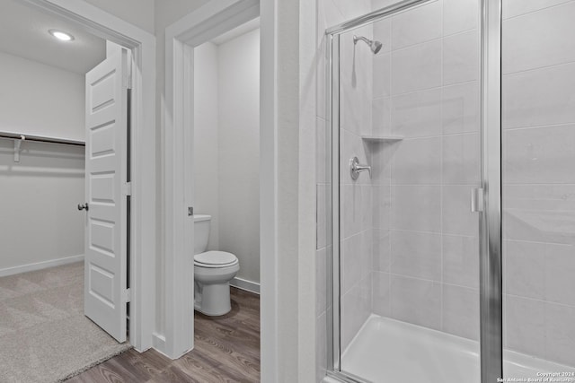 bathroom featuring hardwood / wood-style floors, an enclosed shower, and toilet