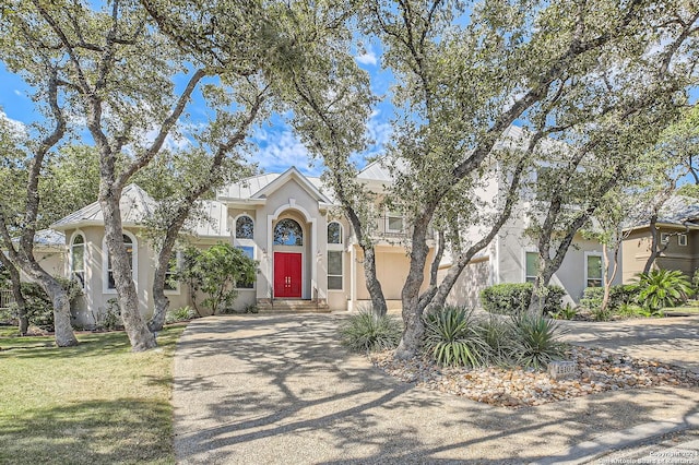 view of front of property with driveway, stucco siding, and a front lawn