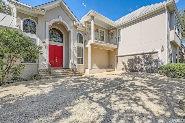 view of front of home with driveway, metal roof, a garage, stucco siding, and a standing seam roof