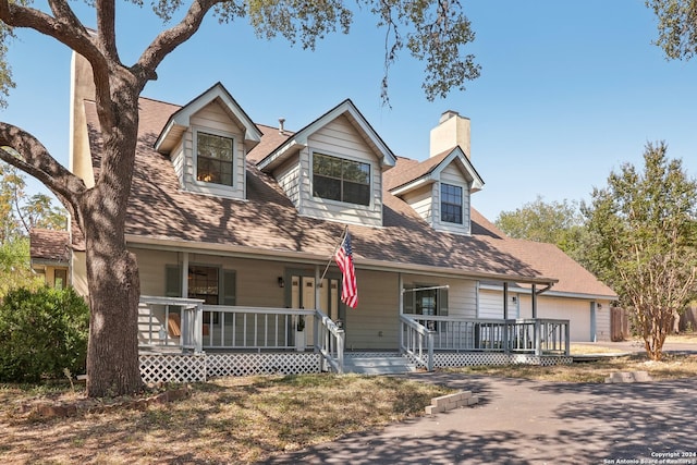 cape cod house featuring covered porch and a garage