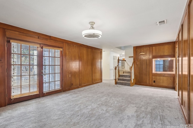 unfurnished living room with light carpet and wood walls