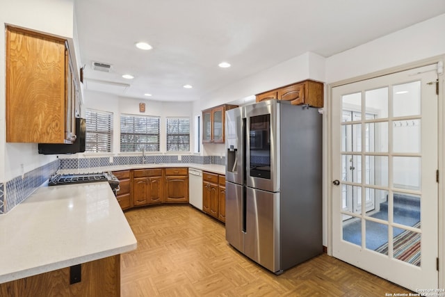 kitchen with stainless steel appliances, backsplash, light parquet flooring, and a healthy amount of sunlight