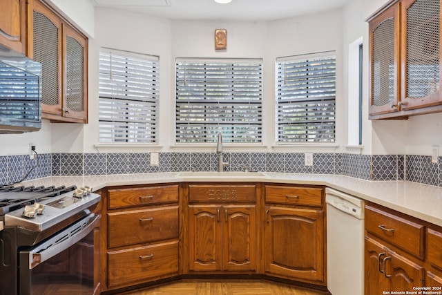 kitchen with light parquet flooring, sink, white appliances, and tasteful backsplash