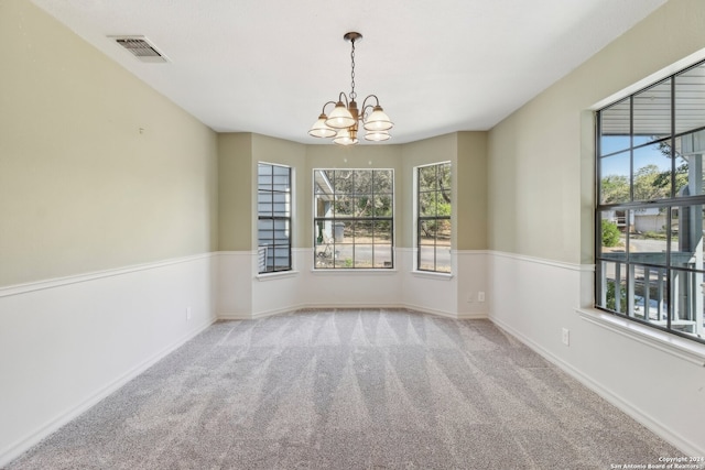 carpeted spare room with an inviting chandelier