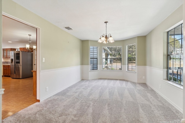 empty room featuring light parquet floors and a chandelier