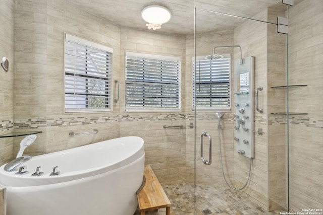 bathroom with tile walls and independent shower and bath