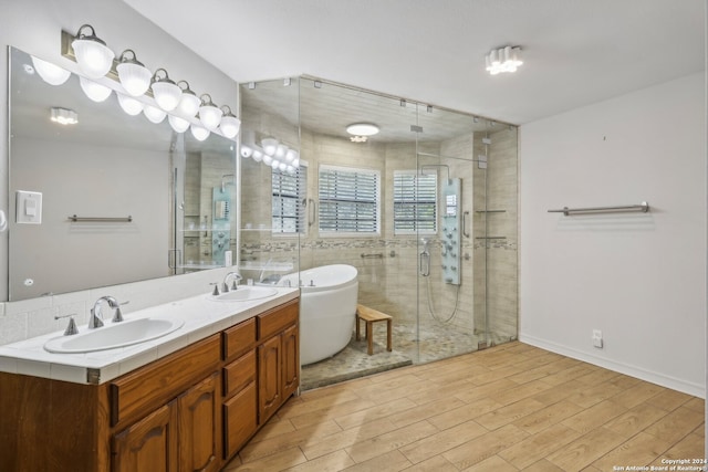 bathroom with plus walk in shower, hardwood / wood-style flooring, and vanity