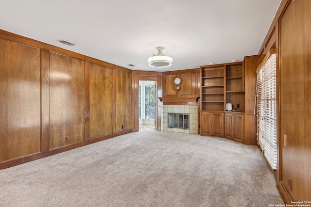 unfurnished living room featuring wood walls, light colored carpet, and a fireplace