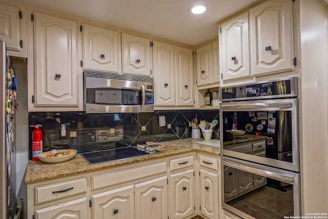 kitchen with backsplash, light stone counters, cream cabinets, and stainless steel appliances