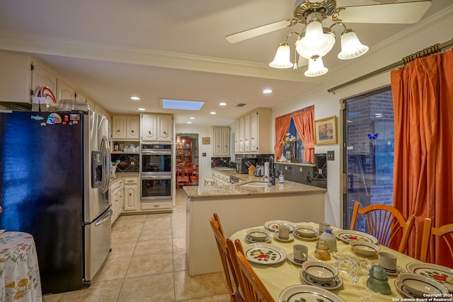 kitchen with a skylight, kitchen peninsula, ornamental molding, and appliances with stainless steel finishes