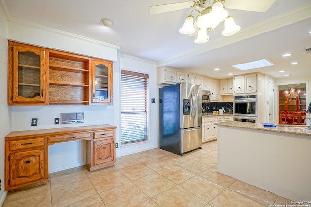 kitchen with backsplash, a skylight, light tile patterned floors, ornamental molding, and appliances with stainless steel finishes