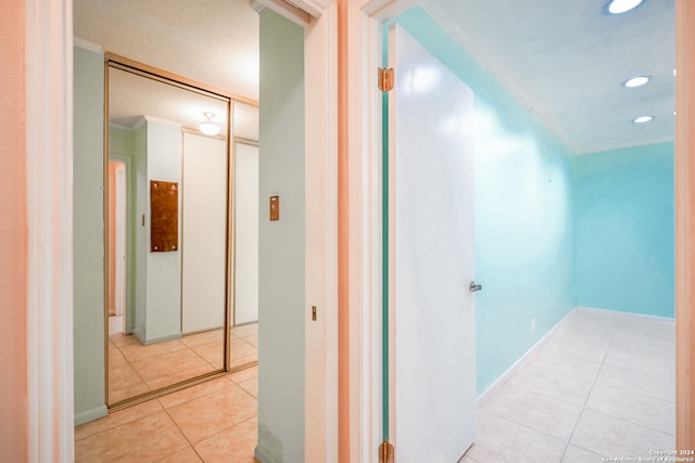 hallway with light tile patterned flooring and ornamental molding