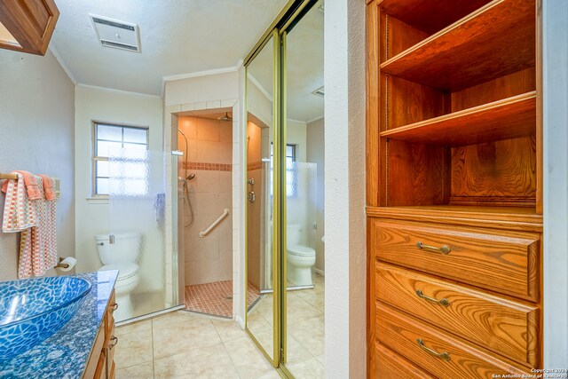 bathroom featuring vanity, a shower with door, tile patterned floors, toilet, and ornamental molding