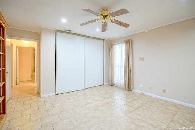 unfurnished bedroom featuring ceiling fan, a closet, light tile patterned floors, and ornamental molding