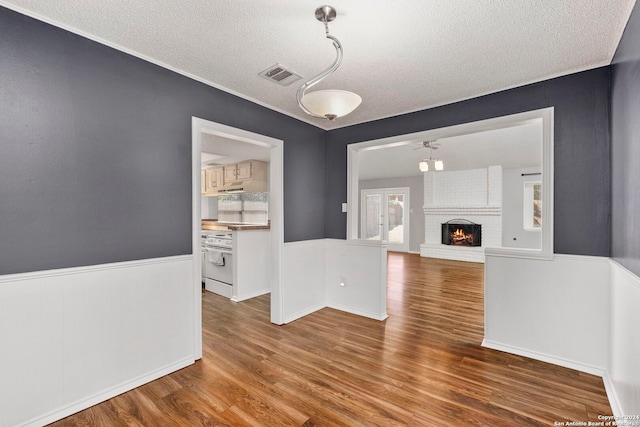 interior space with a fireplace, ceiling fan, hardwood / wood-style flooring, and a textured ceiling