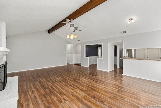 unfurnished living room featuring ceiling fan, hardwood / wood-style flooring, a fireplace, and lofted ceiling with beams