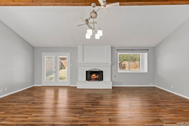 unfurnished living room with lofted ceiling, a brick fireplace, and dark hardwood / wood-style flooring