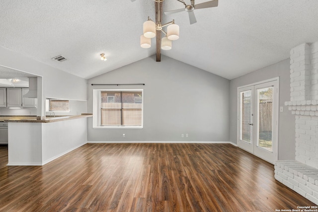 unfurnished living room with ceiling fan, a textured ceiling, plenty of natural light, and dark wood-type flooring