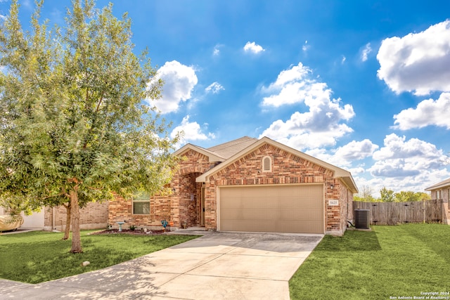 view of front of home with a garage, cooling unit, and a front lawn