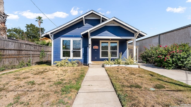 bungalow-style house featuring covered porch and a front yard