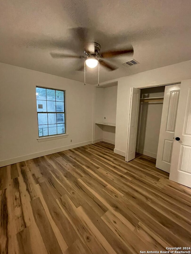 unfurnished bedroom featuring a closet, hardwood / wood-style floors, a textured ceiling, and ceiling fan