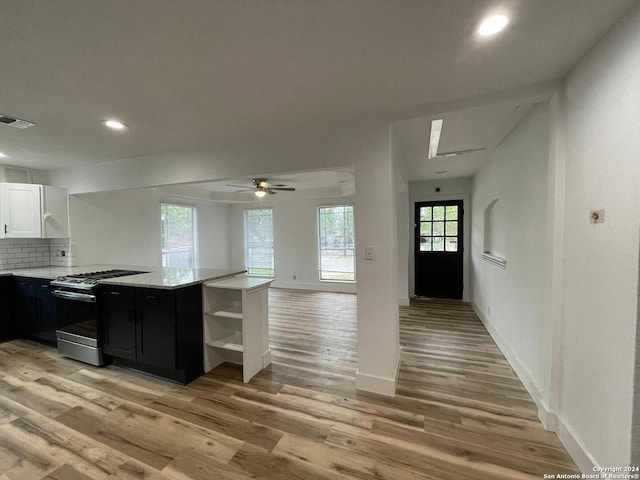 kitchen featuring stainless steel range with gas stovetop, white cabinetry, light wood-type flooring, and plenty of natural light