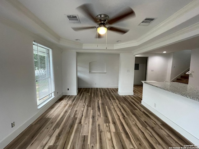 unfurnished living room featuring ceiling fan, a tray ceiling, crown molding, and dark hardwood / wood-style floors