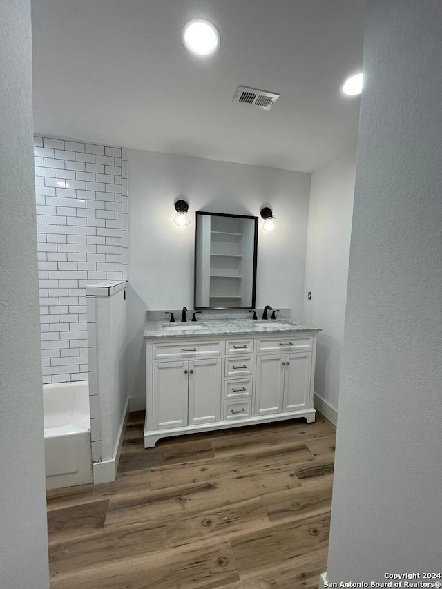 bathroom with a washtub, vanity, and wood-type flooring