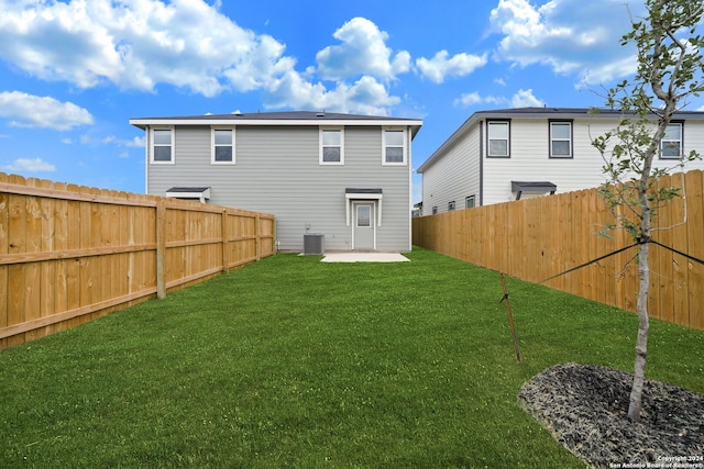 rear view of property with a lawn, a patio area, and central AC