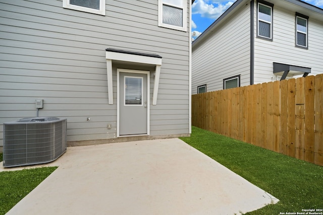 property entrance with a yard, a patio, and central air condition unit