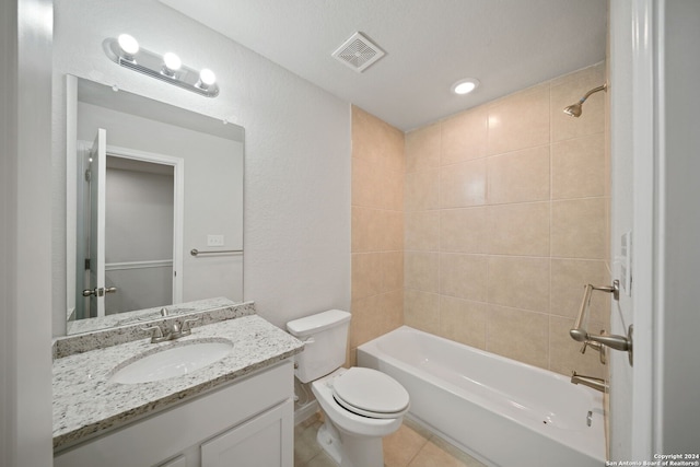 full bathroom with tile patterned flooring, tiled shower / bath, vanity, and toilet