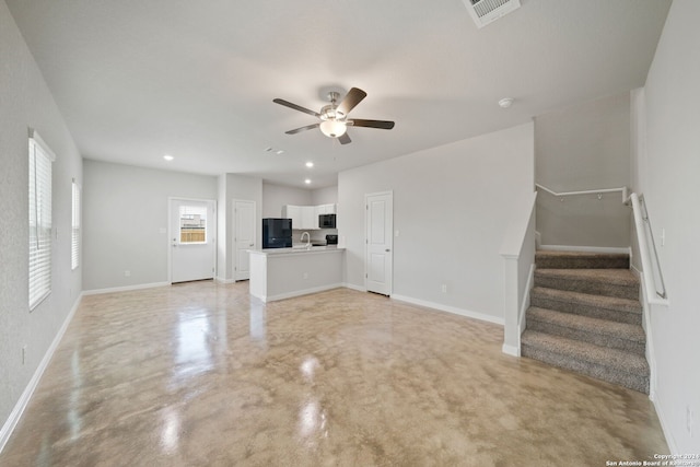 unfurnished living room featuring ceiling fan and sink