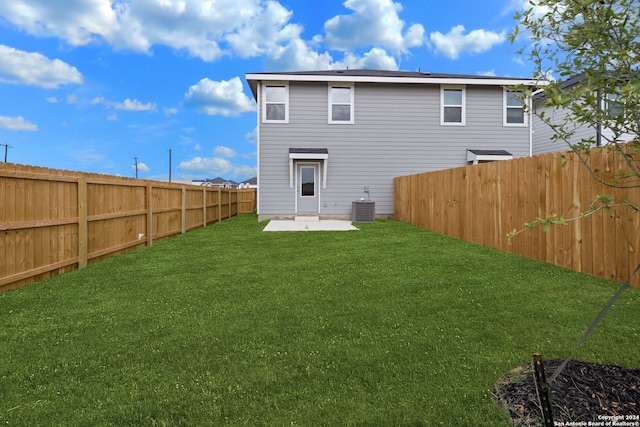 back of property with central AC unit, a patio area, and a yard