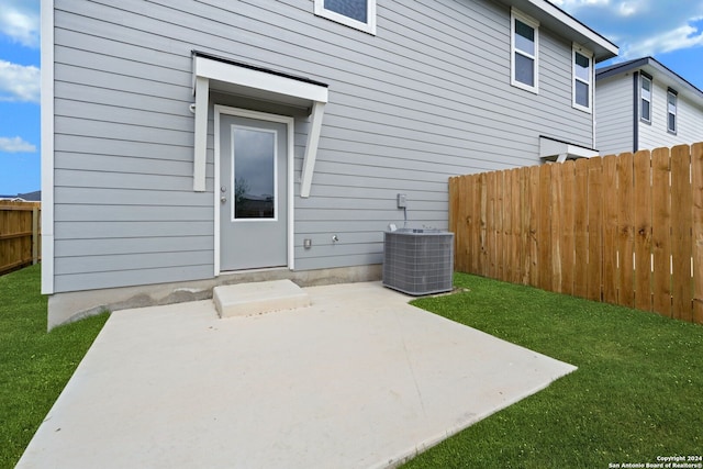 doorway to property with a patio, a lawn, and central AC unit