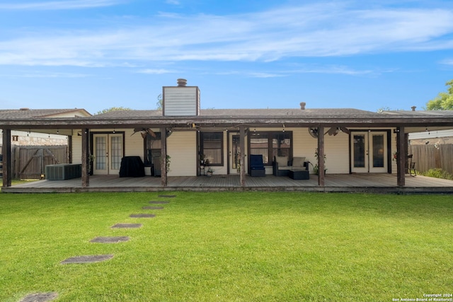 rear view of property featuring central AC unit, a yard, a deck, and french doors