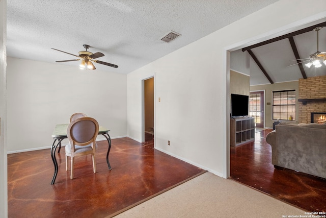 interior space with a brick fireplace, vaulted ceiling with beams, ceiling fan, and a textured ceiling