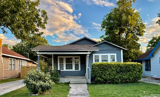 bungalow-style home featuring covered porch and a yard