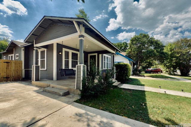 bungalow-style home featuring covered porch and a front lawn