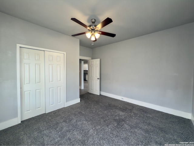 unfurnished bedroom with dark colored carpet, a closet, and ceiling fan