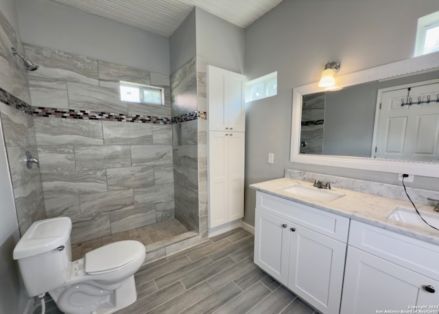 bathroom featuring a tile shower, plenty of natural light, vanity, and toilet