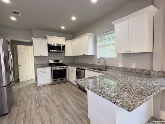 kitchen featuring kitchen peninsula, appliances with stainless steel finishes, white cabinetry, and sink