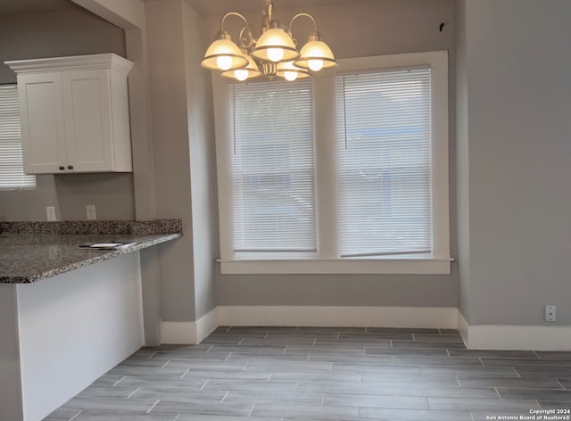 unfurnished dining area with a chandelier and light hardwood / wood-style floors