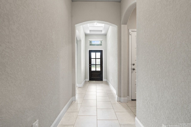 interior space featuring a high ceiling, light tile patterned floors, and a tray ceiling