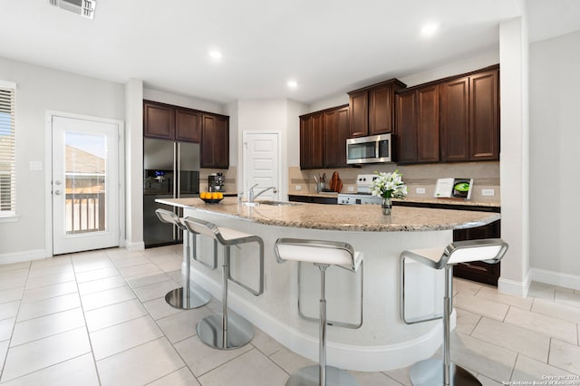 kitchen featuring a center island with sink, appliances with stainless steel finishes, and a breakfast bar area