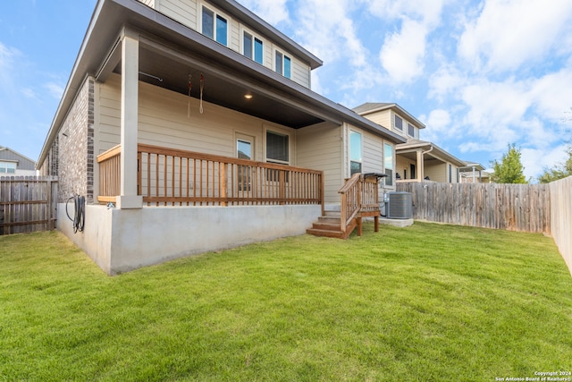 back of property featuring a yard and central AC