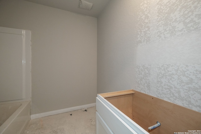 bathroom with concrete floors and a bath