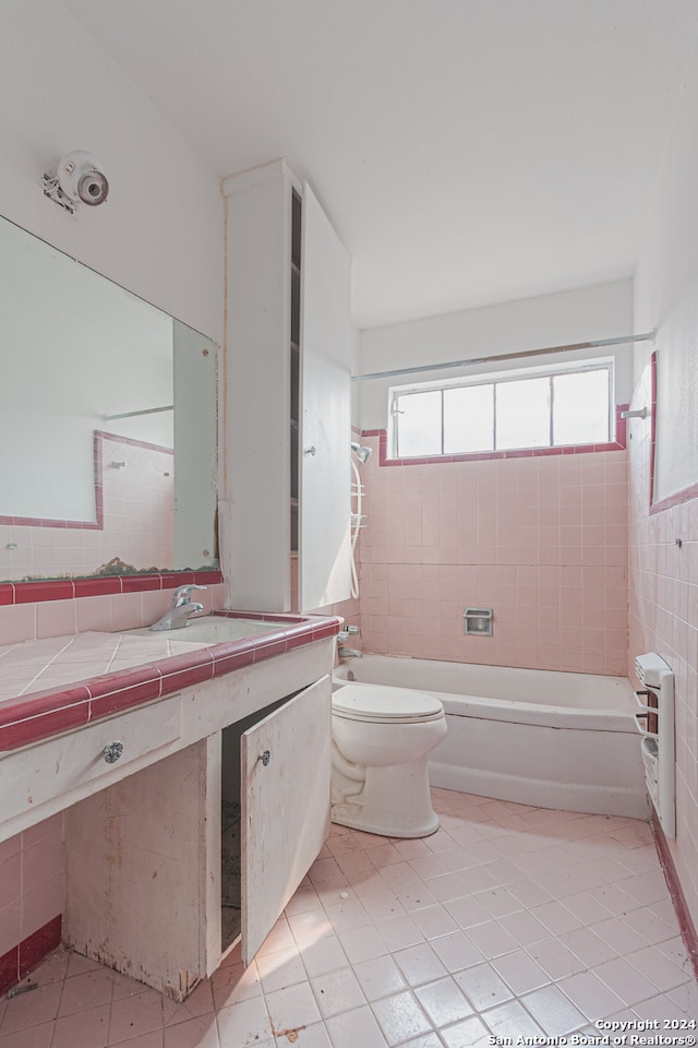 full bathroom with tile walls, vanity, tiled shower / bath combo, tile patterned flooring, and toilet