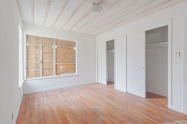 unfurnished bedroom with light hardwood / wood-style flooring and two closets