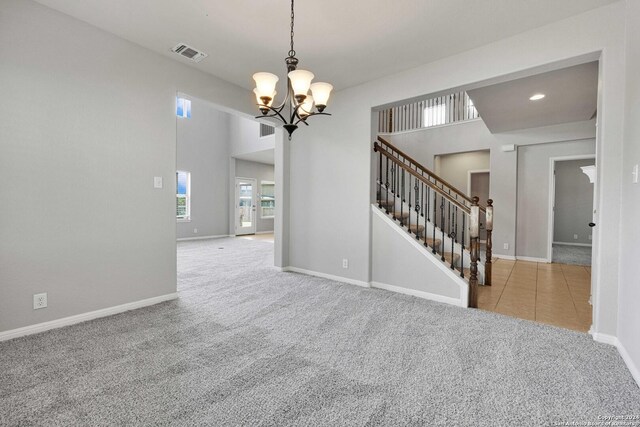 carpeted spare room with a notable chandelier