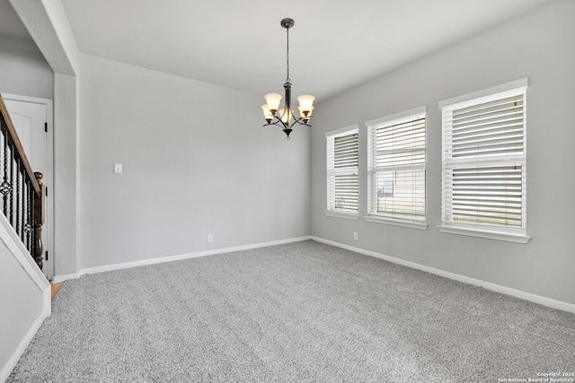 carpeted spare room with a chandelier